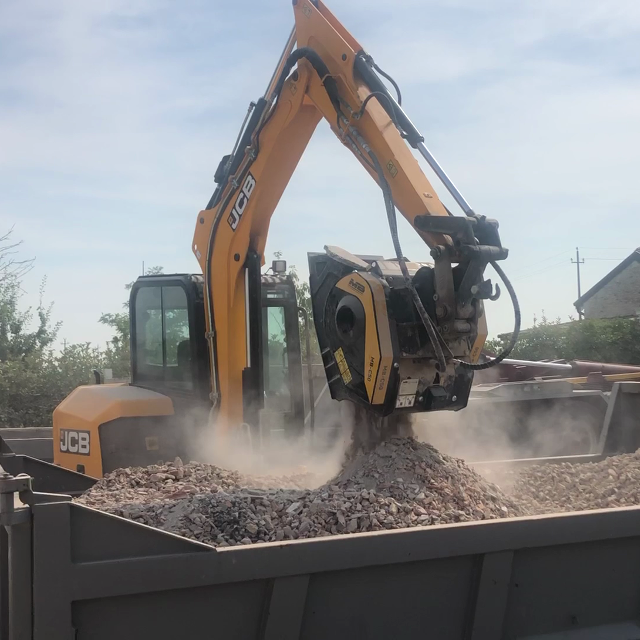 Backenbrecherlöffel MB Crusher C50 S4 auf einem JCB Bagger, beladen eines Anhängers